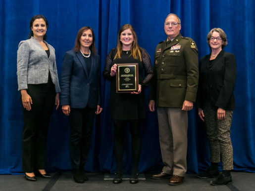 Individuals posing with an award plaque.