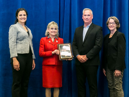 Individuals posing with an award plaque.