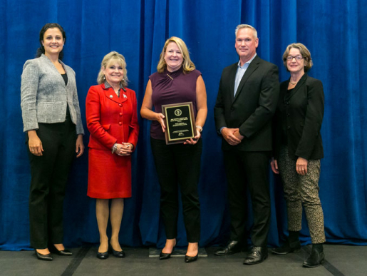 Individuals posing with an award plaque.