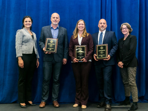 Individuals posing with an award plaque.