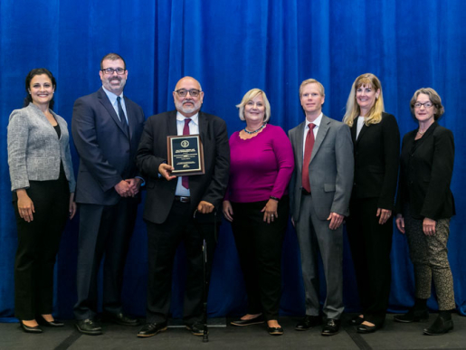 Individuals posing with an award plaque.