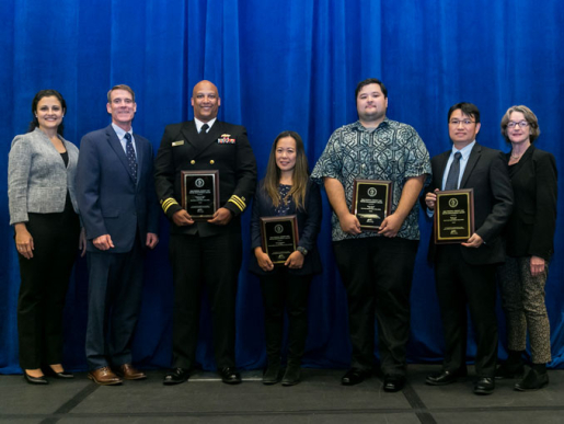 Individuals posing with an award plaque.