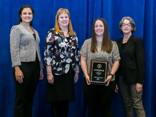 Individuals posing with an award plaque.