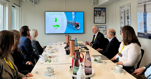 People face each other at a boardroom table.