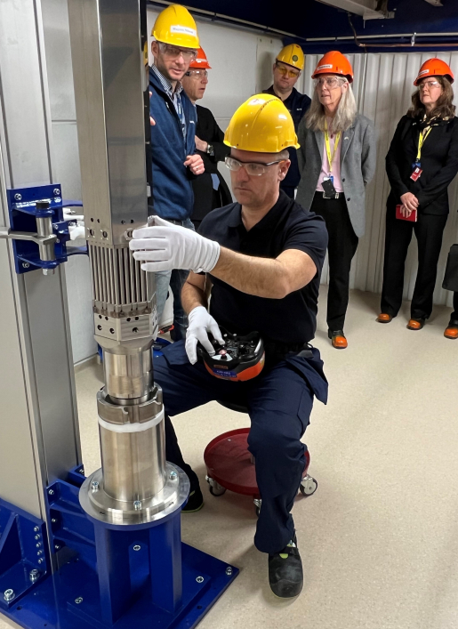 A Westinghouse Sweden employee adjusts the mock-up of the company’s VVER-440 fuel rod assembly as a group of people look on.