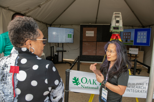 Three people standing and talking at a display for Oak Ridge National Lab.