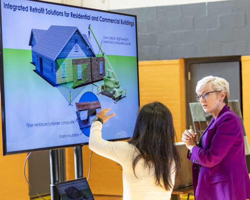 Two people, one being Energy Secretary Jennifer Granholm, standing in front of a screen discussing what's displayed on it.