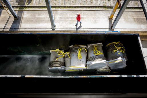 Photo looking down at person walking and large container.