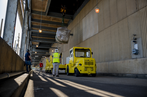 Photo of person in reflective vest overseeing movement of equipment.