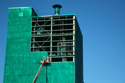 Large building painted green under demolition. 