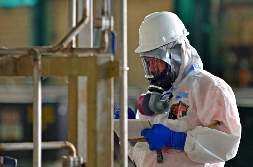 Worker wearing protective gear inspects equipment.