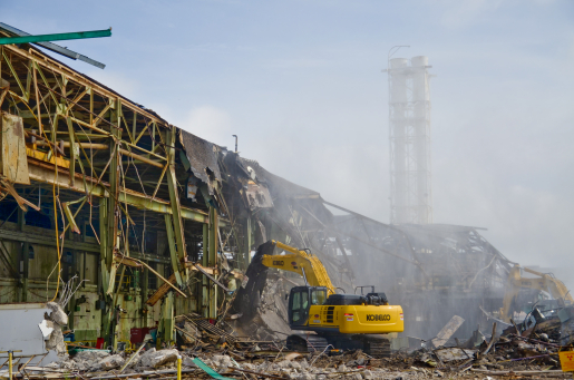 Excavator shears debris from building. 