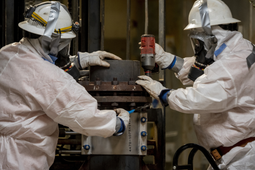 Two workers in full protective gear.