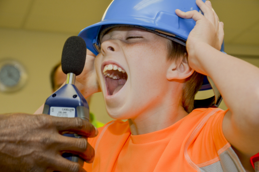 Student screams into an instrument to measure noise levels.
