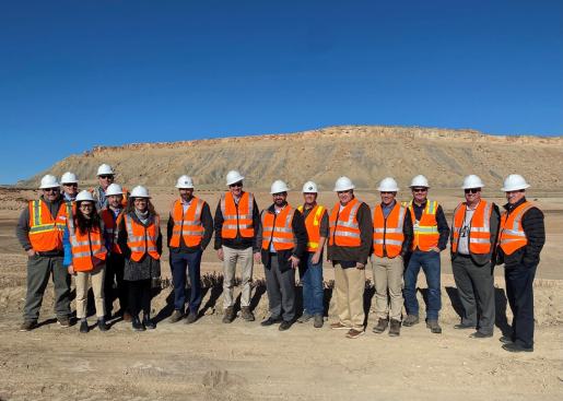 Group of people in reflective vest and hard hats pose outside for a group photo.