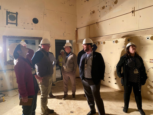 A Group of people with hard hats on standing in an old building.