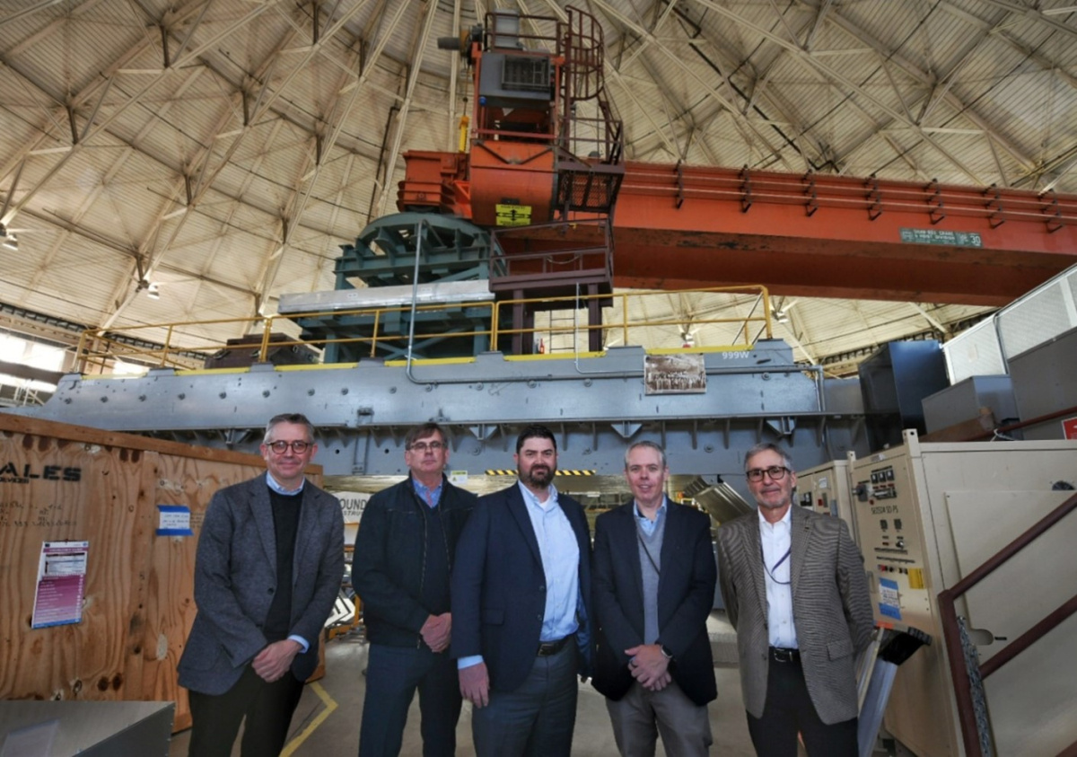 A group of people pose in front of heavy equipment for group photo.