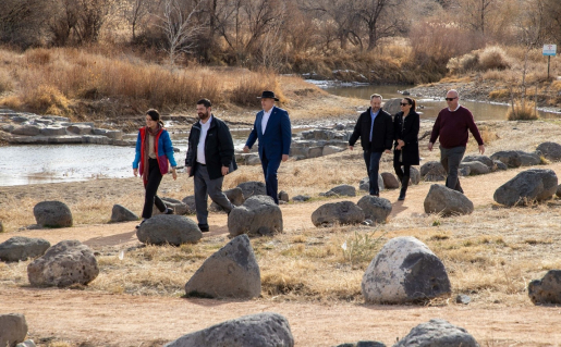 A group of people walking alongside a river.