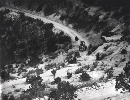 A dirt road on the side of a tree covered mountain