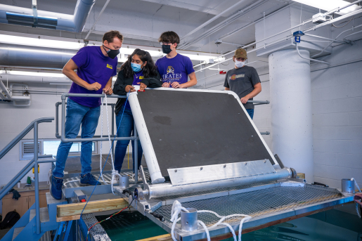 People standing over a wave tank with a marine energy device