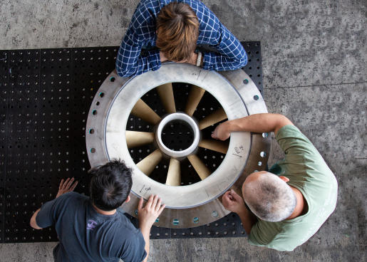 Workers standing over a prototype guide vane housing