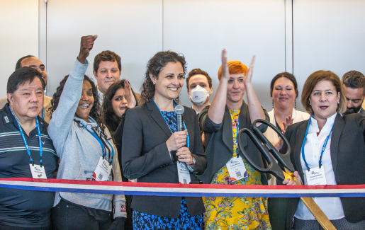 A group of people standing behind a ribbon for a ribbon-cutting ceremony.