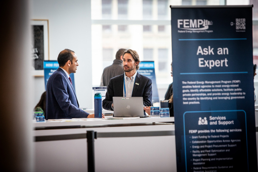 Two conference attendees talking to each other next to a sign that reads, "Ask an Expert."