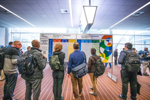 Conference attendees looking at a big poster with the event schedule.