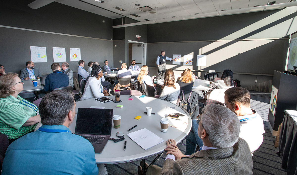 Attendees of a conference sitting around large round tables.