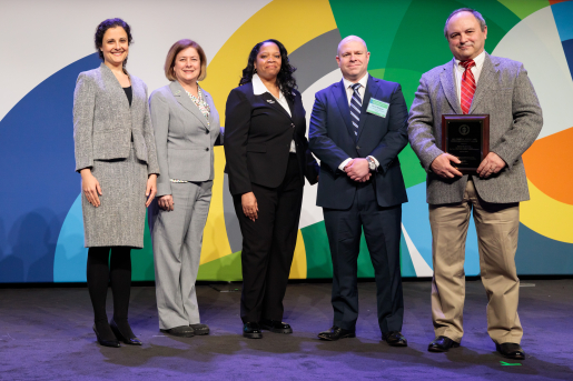 A group of individuals at an awards ceremony smiling at the camera.