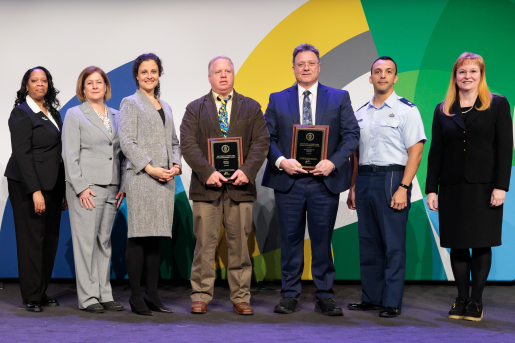 A group of individuals at an awards ceremony smiling at the camera.