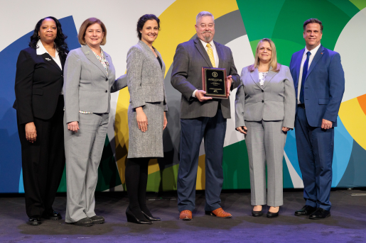 A group of individuals at an awards ceremony smiling at the camera.