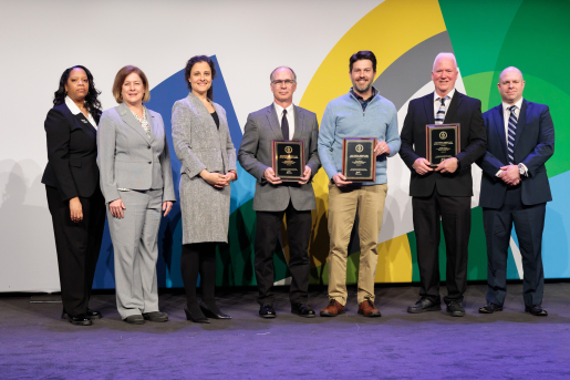 A group of individuals at an awards ceremony smiling at the camera.