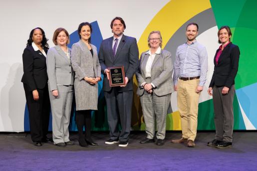 A group of individuals at an awards ceremony smiling at the camera.