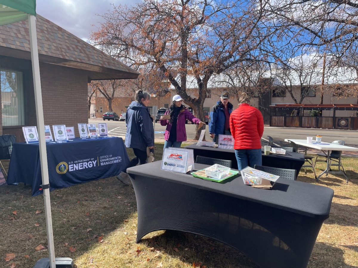 A group of people stand around informational table booths