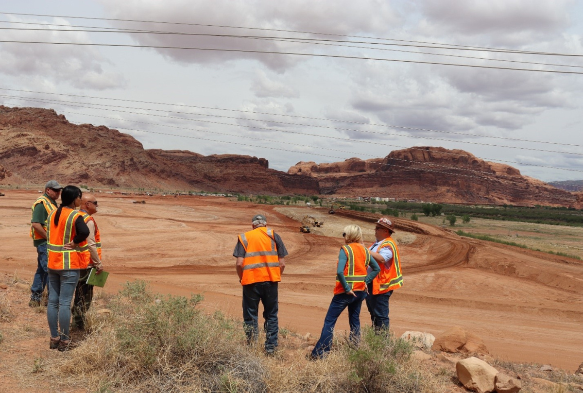 People in safety gear stand in an open area at the Moab Site