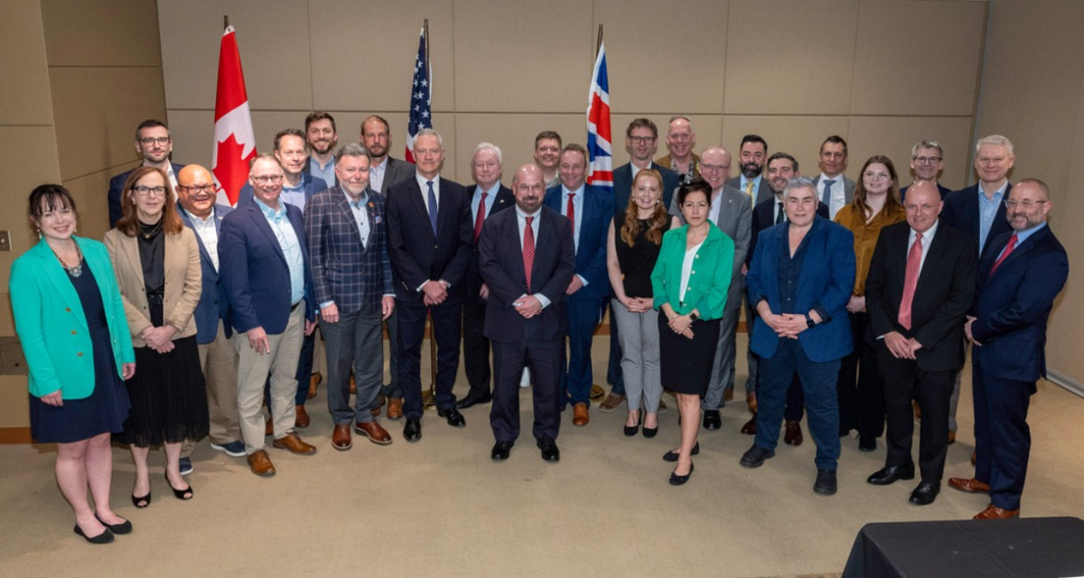 Group photo of professionals posing in front of three flags