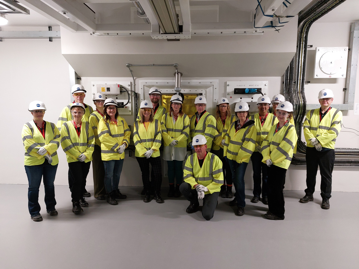 A group of people in yellow protective vests and white hard hats posing for a picture