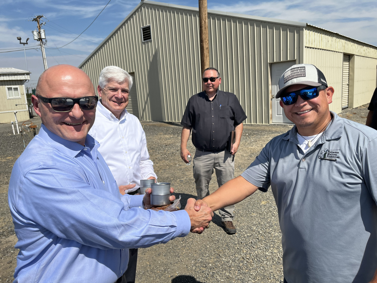 Two professionals shaking hands outside at a site tour and smiling at the camera