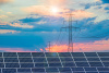 Photo of solar panels against a backdrop of sky and transmission lines