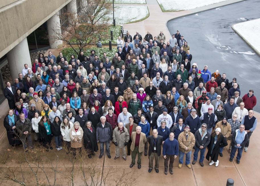 Arial photograph of a group of large group of people lined up and looking up at the camera.
