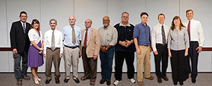 Photo of 11 adults, both male and female, standing in a row.