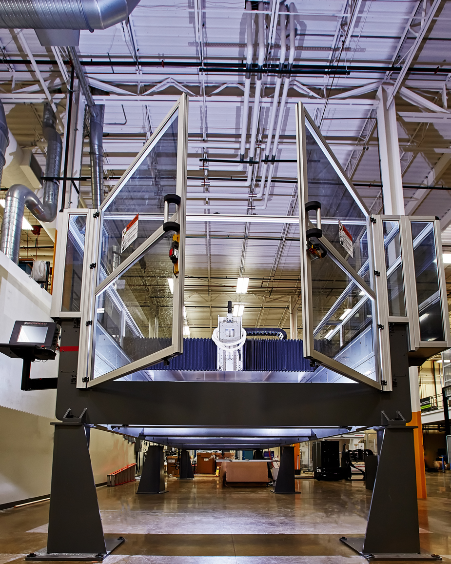 Oak Ridge National Laboratory has developed the Big Area Additive Manufacturing machine, which is being used to apply 3-D printing processes to manufacture wind turbine components for use in Energy Department research. The groundbreaking tool is capable of printing objects that are 10 times larger at speeds up to 1,000 times faster than today’s industrial additive machines. <em>Photo from Oak Ridge National Laboratory</em> Photo of a large machine in a warehouse-style building.