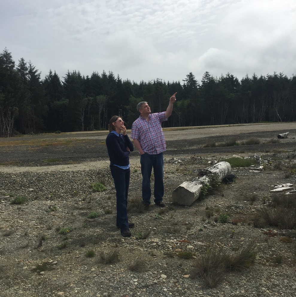 Office of Indian Energy Deputy Director David Conrad and National Renewable Energy Laboratory Resilience Lead Eliza Hotchkiss on a site visit to the Quinault Indian Reservation. Photo by Sherry Stout, NREL Photo of two people in a field.