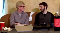 Photo of two men sitting on a couch talking to each other.