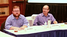 Photo of two men sitting at a table, facing the camera.