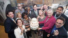 Michigan Saves staff celebrate their $50 million energy investment milestone. Photo: Trumphie Photography. Photo of a group of people holding a cake and looking toward the camera.