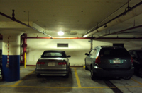 Photo of cars in a parking garage with an LED fixture on the ceiling above.
