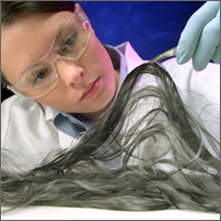 Researcher with tweezer holding up carbon fibers recovered from a epoxy-based polymer matrix composite.