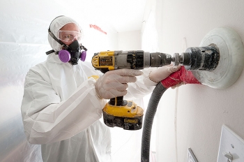 A weatherization worker drills holes to blow cellulose insulation in the interior walls of this home. | Photo courtesy of Dennis Schroeder, NREL A weatherization worker drills holes to blow cellulose insulation in the interior walls of this home. | Photo courtesy of Dennis Schroeder, NREL